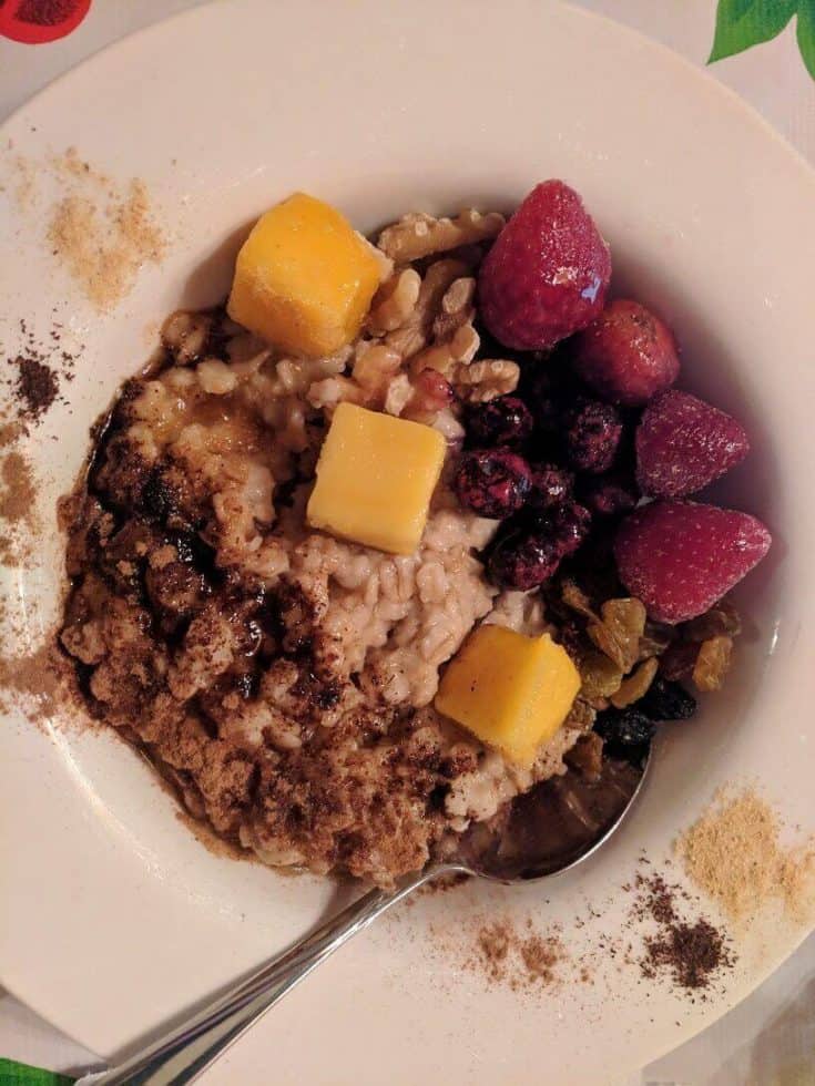 oatmeal in a bowl with spoon, berries and mango