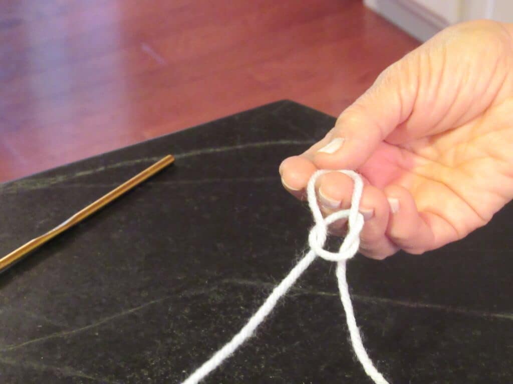 Hand with white yarn making a slipknot