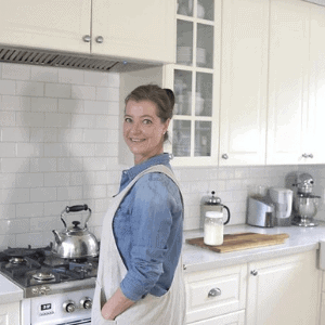 Smiling woman in apron at stove with kettle