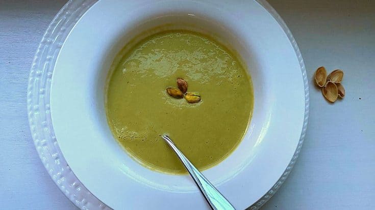 green asparagus soup with pistachios white bowl and spoon