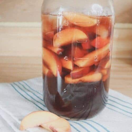 mason jar with peaches and tea on cloth