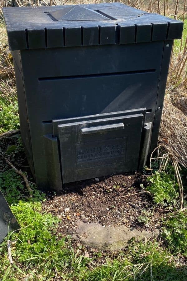 Black cube shaped easy composting bin, dirt, green plants, rocks